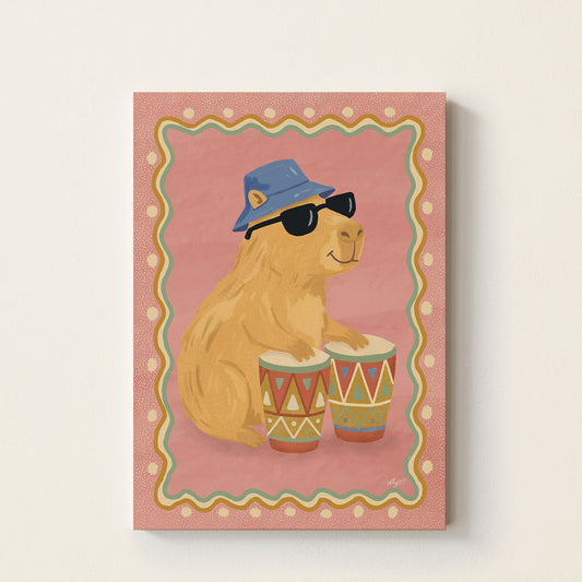 Capybara drum poster featuring a capybara wearing sunglasses and a blue bucket hat playing colorful drums on a pink background.