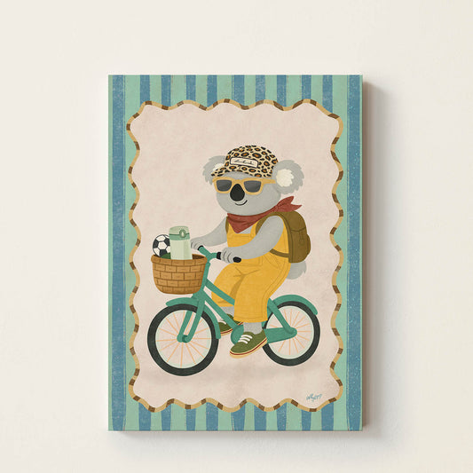 Hand-drawn koala wearing sunglasses and a backpack while riding a vintage bicycle with a picnic basket and soccer ball, whimsical adventure wall art for kids' bedrooms, nurseries, and playrooms.